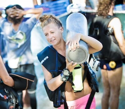 A diver carries her tank from the boat.